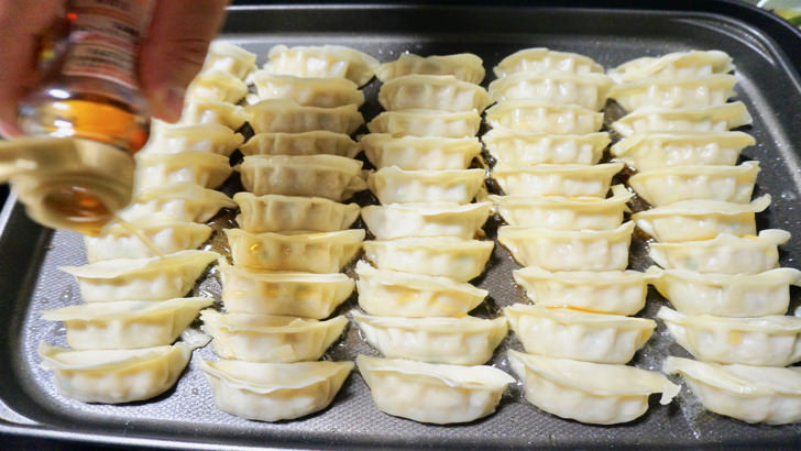 コストコの冷凍黒豚餃子(ホットプレートの上にごま油を投入)