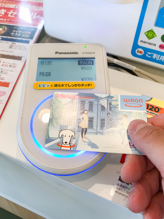 吉野家でWAONで支払うため端末にカードをかざす